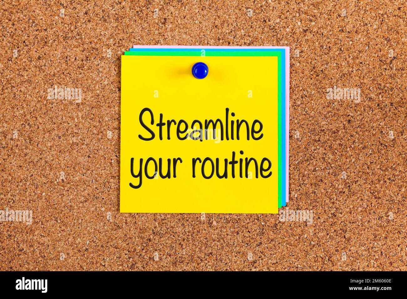 Gelber Zettel mit Wörtern strafft Ihre Routine auf Korkbretthintergrund Stockfoto