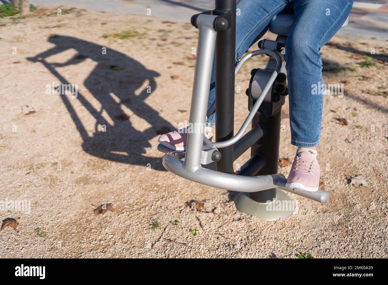 Details von Frauenbeinen, die in einem öffentlichen Apparat in einem Stadtpark Gymnastik machen. Stockfoto