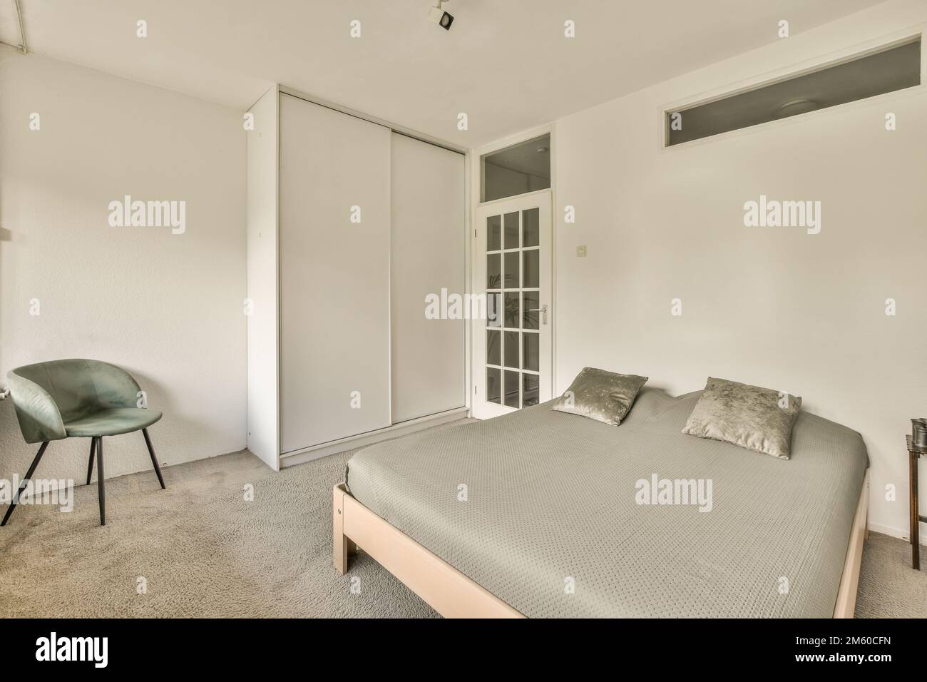 Ein Schlafzimmer mit einem Bett, Stuhl und Schränken in der Rückwand zur anderen Seite des Zimmers Stockfoto