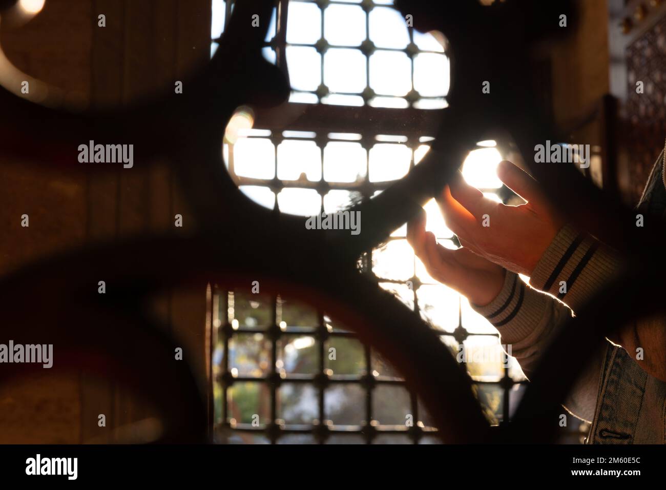 Islamisches Foto. Muslimischer Mann betet in der Moschee hinter den Zäunen. Selektive Fokussierung auf die Hände. Ramadan oder kandil oder Laylat al-qadr oder islamisches Konzert Stockfoto