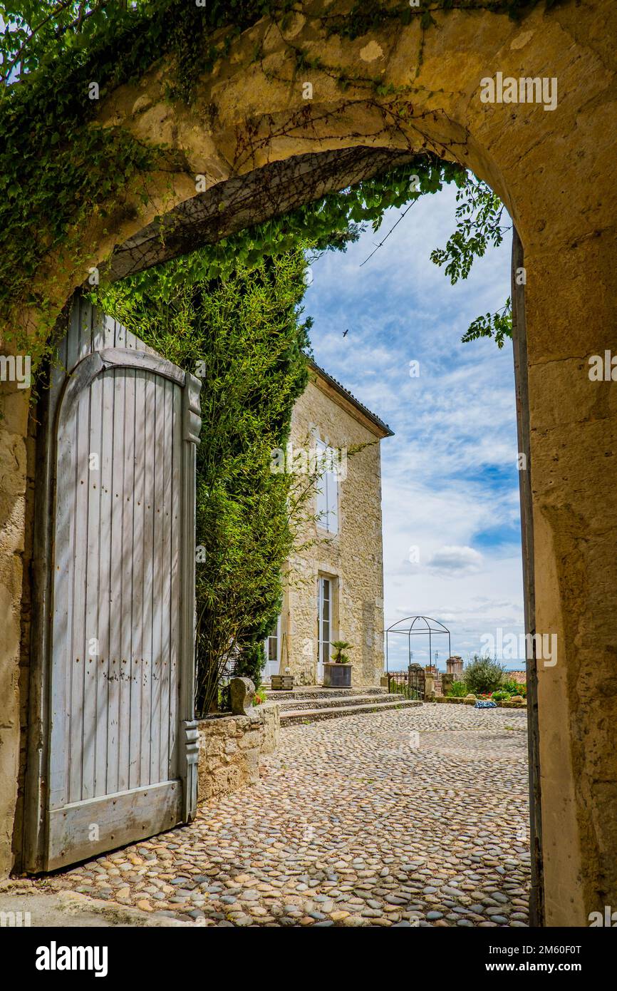 Eingang zu einem wunderschönen gepflasterten Hof und einem traditionellen Steinhaus in Lectoure, im Süden Frankreichs (Gers) Stockfoto