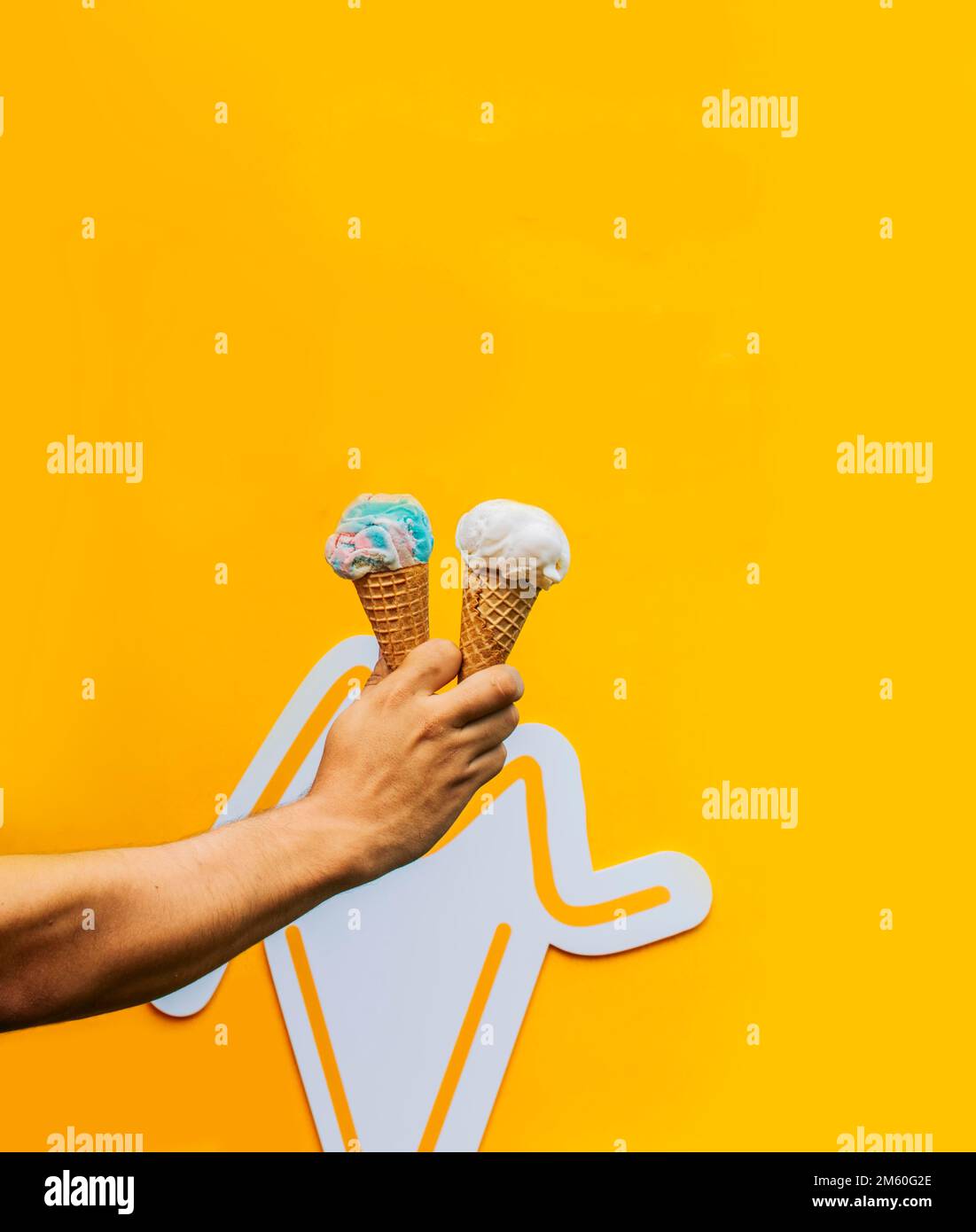 Eine Hand, die zwei Waffeleis isoliert hält. Hand hält zwei Eiskegel auf gelbem Hintergrund. Waffelkonus-Eiscreme-Konzept auf Gelb Stockfoto