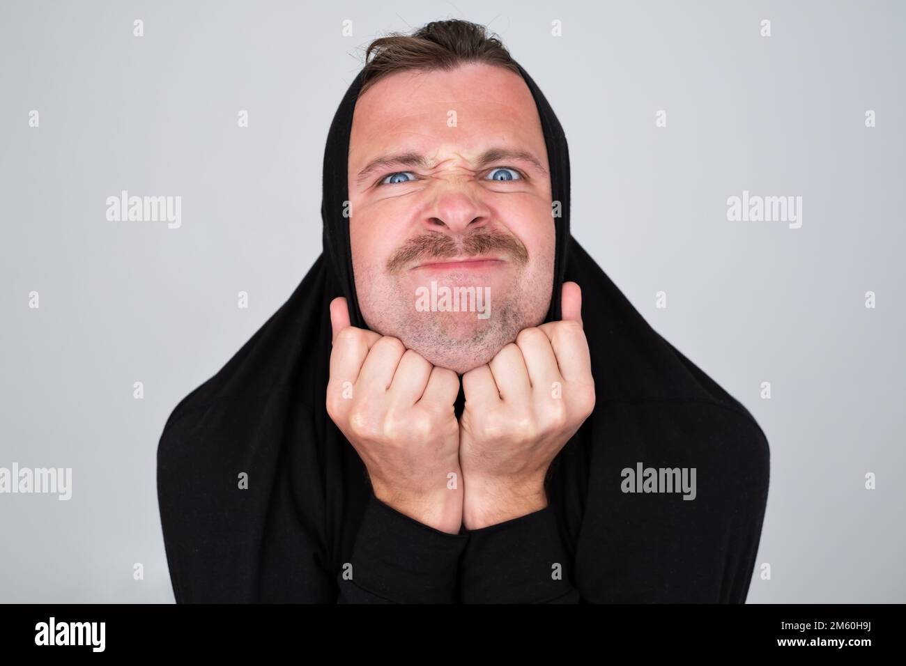 Ein Mann versteckt sich, der Pullover auf den Kopf zieht, und verärgert ist. Stockfoto