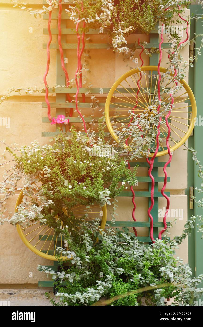 Dekoration urbane Kunst Objekt von Fahrradrädern und bunten eleganten Blumen an der Wand Stockfoto