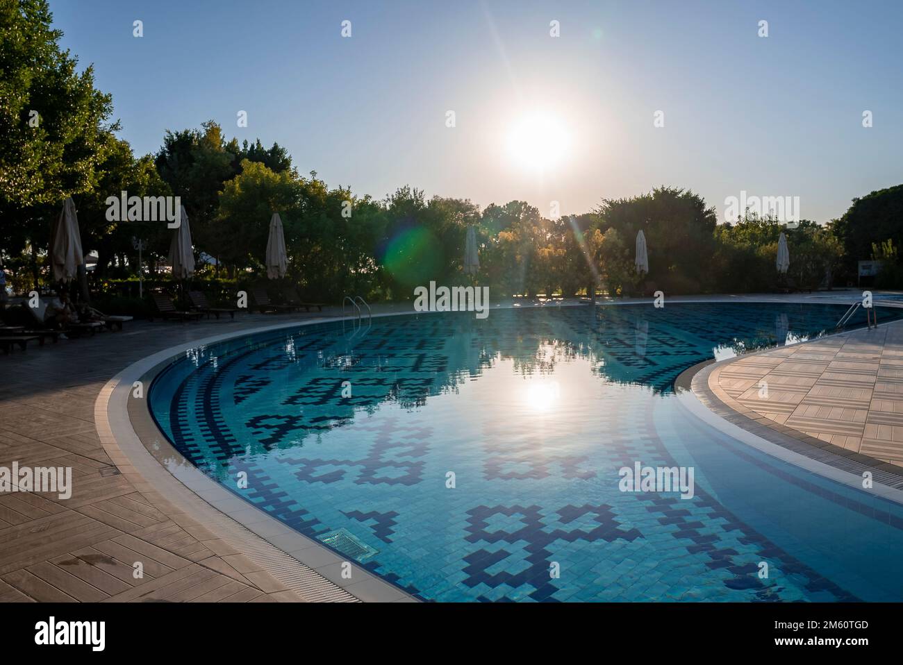 Liegestühle und Sonnenschirme werden vom geschwungenen Pool des Resorts angeordnet Stockfoto