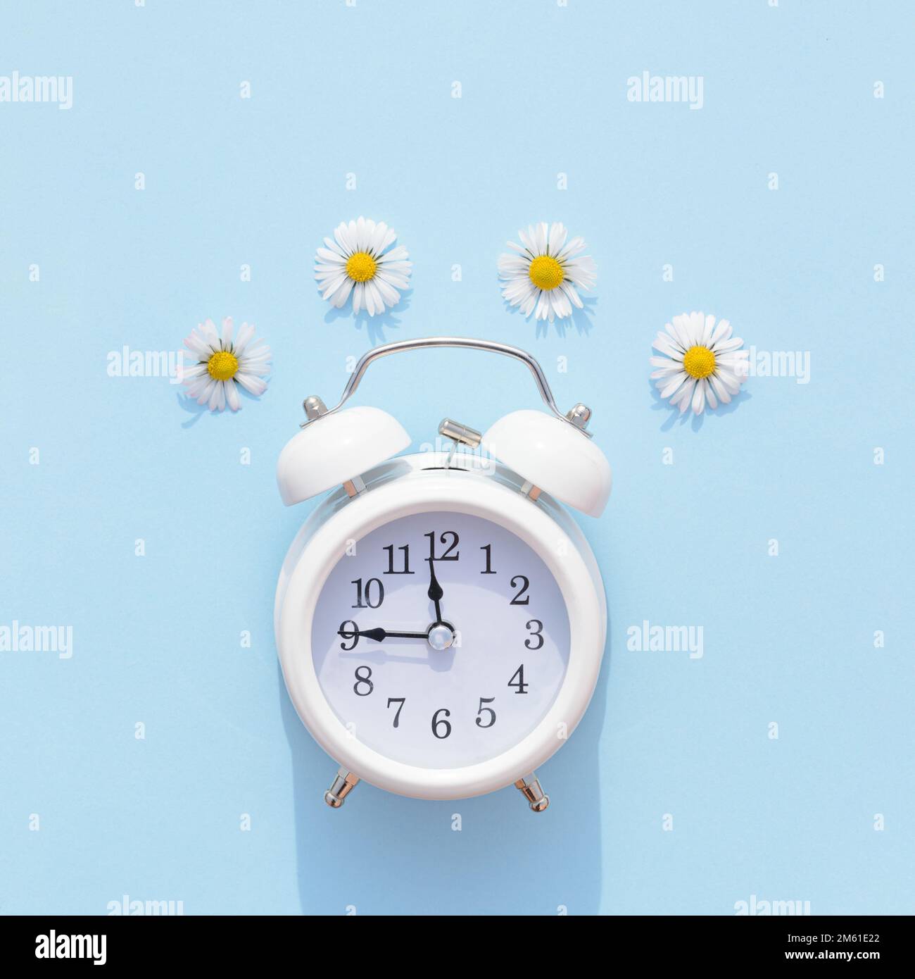 Alte Retro-Uhr auf blauem Hintergrund mit Frühlingsblumen. Ästhetisches Frühlingskonzept. Stockfoto