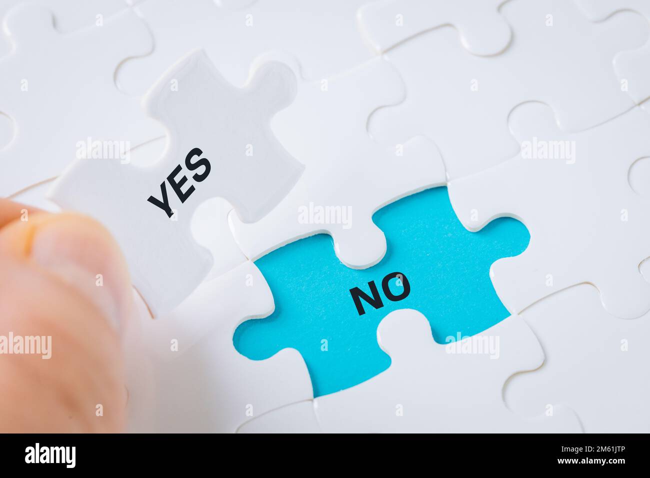 Ja, nein, die weiße Puzzle-Hand nimmt das Wort "Ja" auf und enthüllt das Wort "Nein" auf blauem Hintergrund, Konzept, Zustimmung und Ablehnung und trifft eine Entscheidung Stockfoto