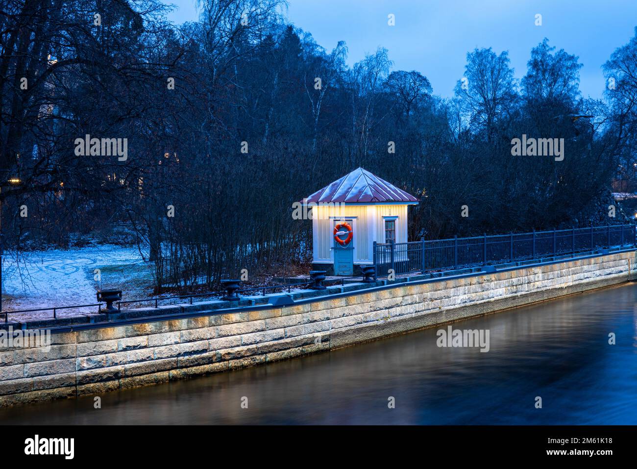 Beleuchtete kleine Hütte am Ufer der Tammerkoski-Stromschnellen vor Sonnenaufgang in Tampere, Finnland Stockfoto