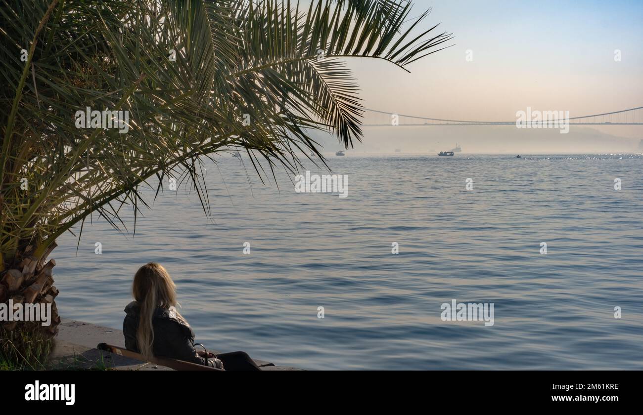 Einsame Frau, die allein am Meer sitzt. Einsame Frau, die allein am Meer sitzt. Stockfoto