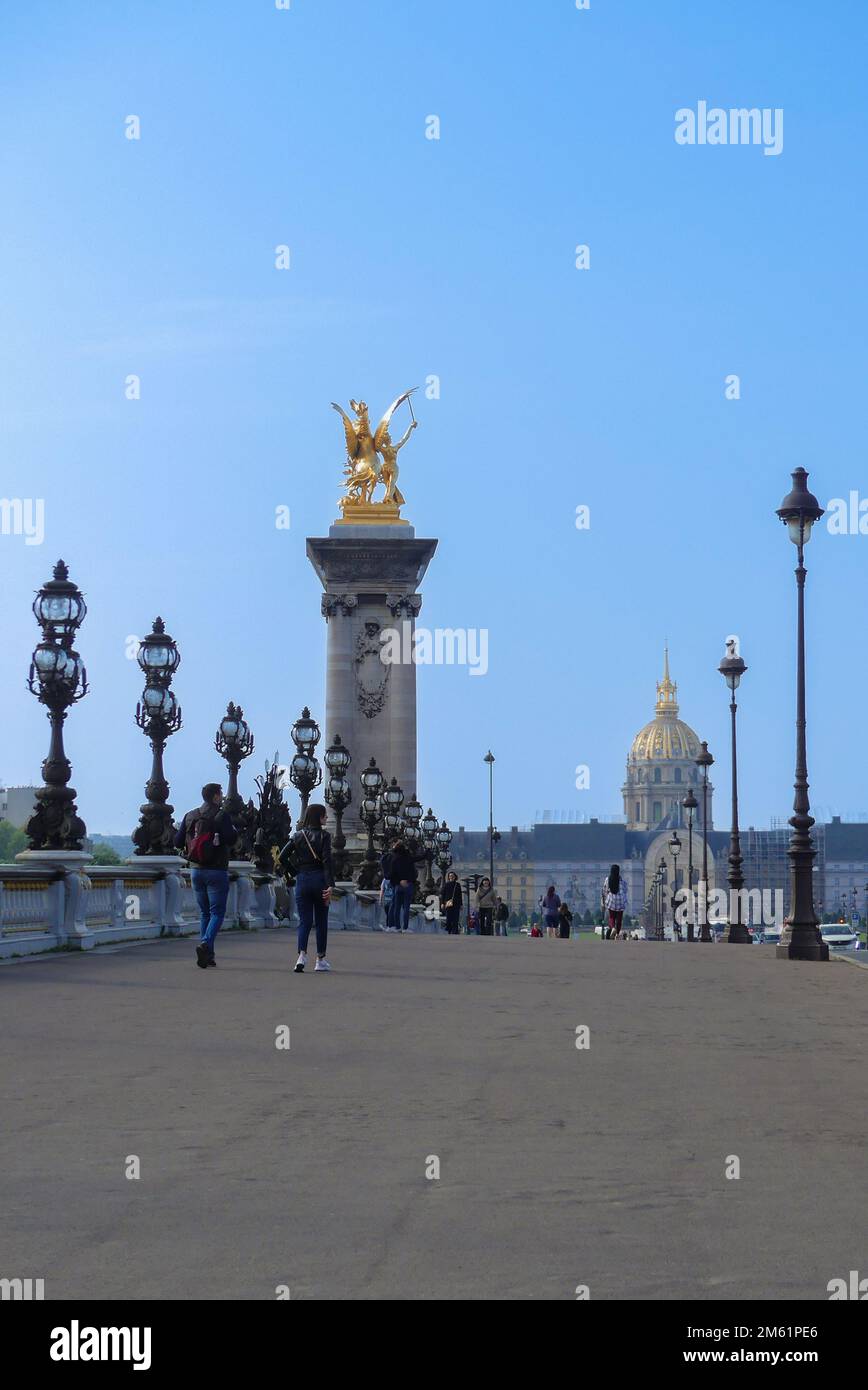 Paris, Frankreich. April 24. 2022. Ein Mann und eine Frau auf der berühmten Pont Alexandre III Historisches Denkmal. Hotel des Invalides im Hintergrund. Stockfoto