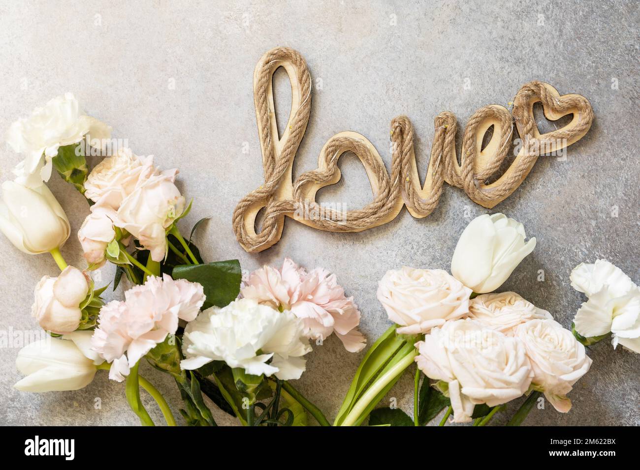 Valentinstagskarte mit „Love“-Buchstaben und wunderschönen Frühlingsblumen auf hellgrauem Hintergrund. Valentinstag, Frauentag, Muttertag Konz Stockfoto