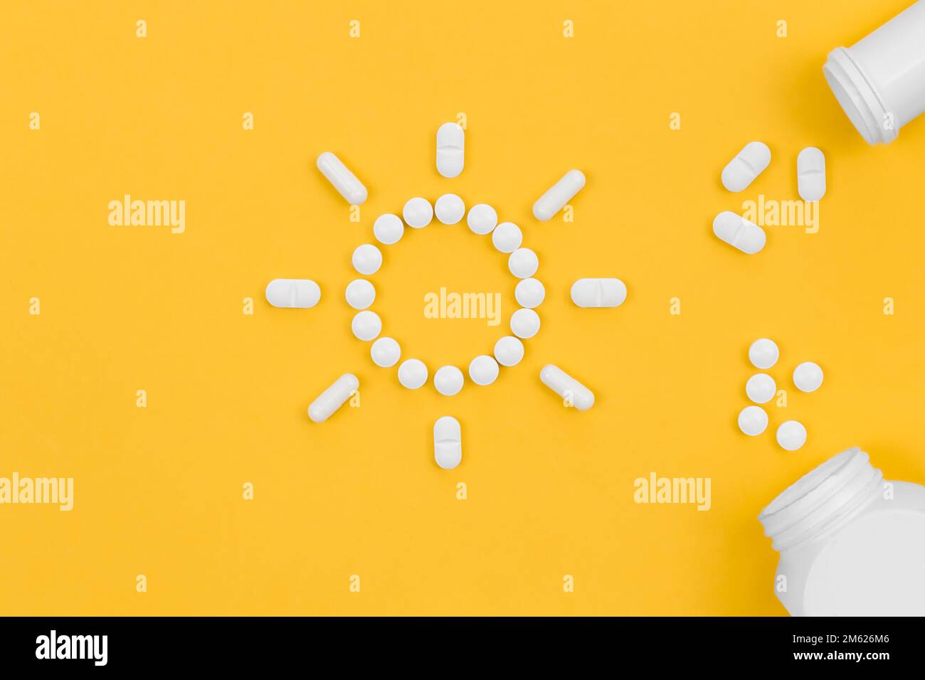 Pillen in Form der Sonne, auf gelbem Hintergrund, flach liegend. Stockfoto