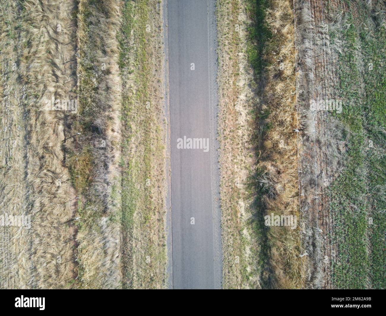 Leere Draufsicht der Straße mit Asphaltfläche und grünen Randfeldern auf jeder Seite. Victoria, Australien. Stockfoto