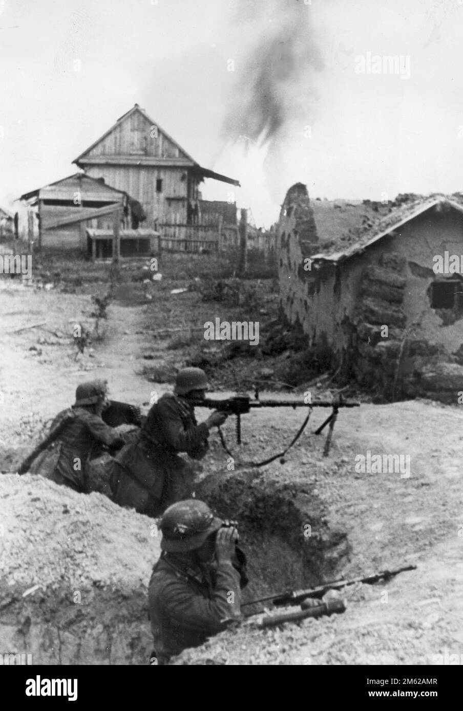 Drei deutsche Soldaten (einer davon mit einem MG-34-Gewehr) in einem Graben zwischen Dorfgebäuden in der Nähe von Stalingrad während der Schlacht von Stalingrad WW2 Stockfoto