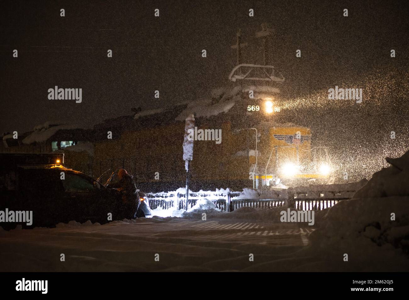 Truckee, USA. 31. Dezember 2022. Eine Eisenbahnmaschine der Union Pacific wird durch den Schneesturm geschleudert, während eine Person den Schnee von ihrem Auto entfernt. Heftige Regen- und Schneefälle beeinflussten einen Großteil der Sierra Nevada Mountains. Truckee, Kalifornien. 31. Dezember 2022. (Foto: Hale Irwin/SIPA USA) Guthaben: SIPA USA/Alamy Live News Stockfoto