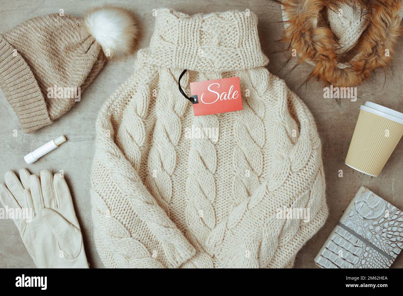 Winterdecke mit Mütze, Schal, Handschuhen, Kaffeetasse, Verkaufsanhänger und Pullover. Stockfoto