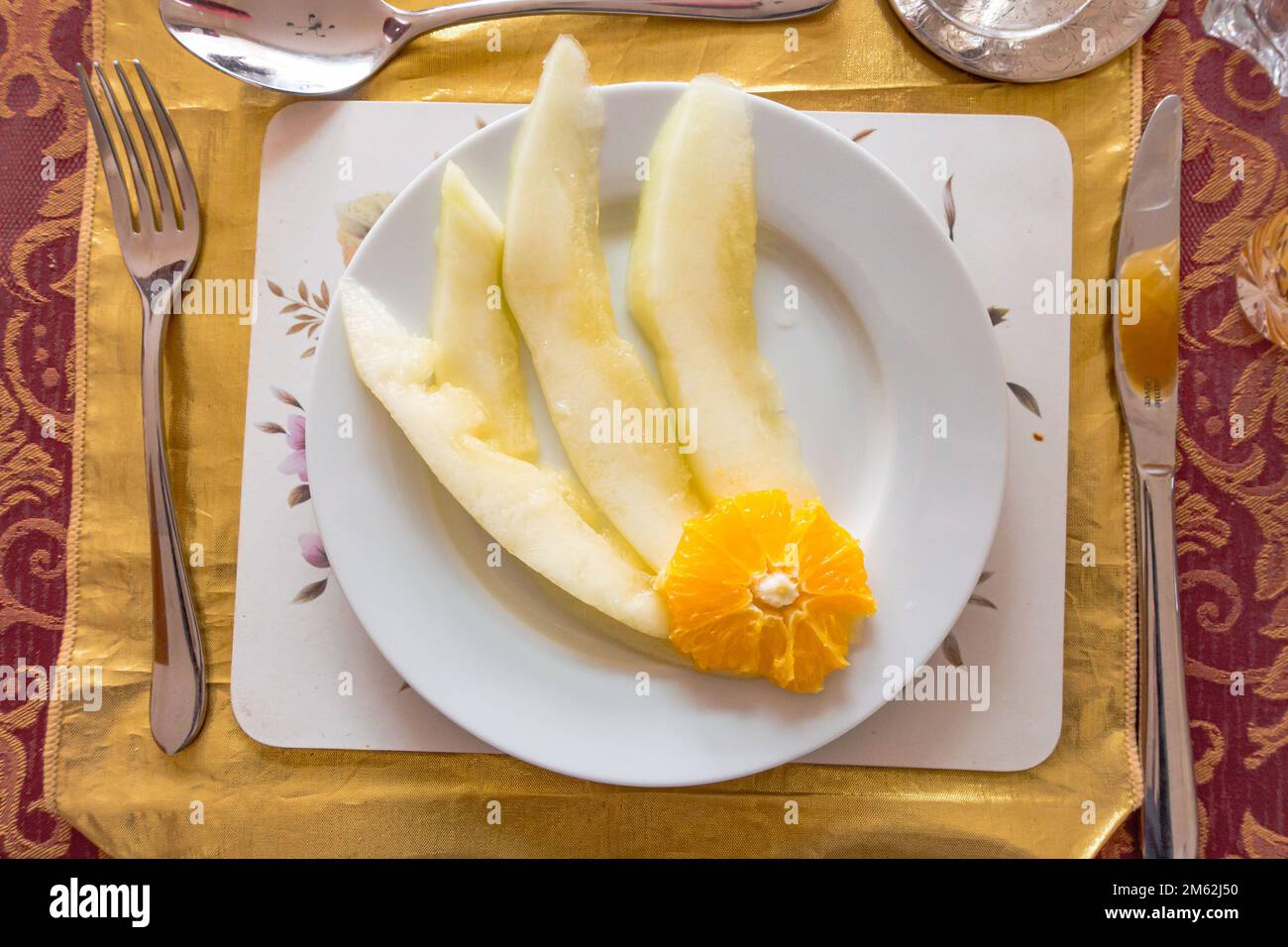 Scheiben Honigmelone garniert mit einer Scheibe Orange als Vorspeise in einem 3-Gänge-Menü. Stockfoto