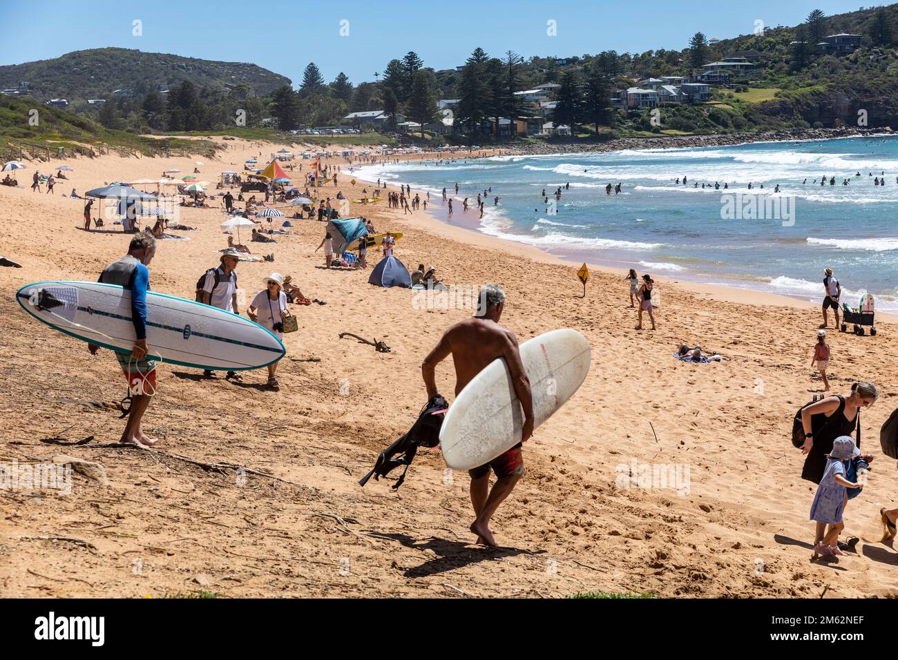 Zwei ältere grauhaarige Männer mittleren Alters tragen ihre Surfbretter in Avalon Beach, Sydney, Australien Stockfoto