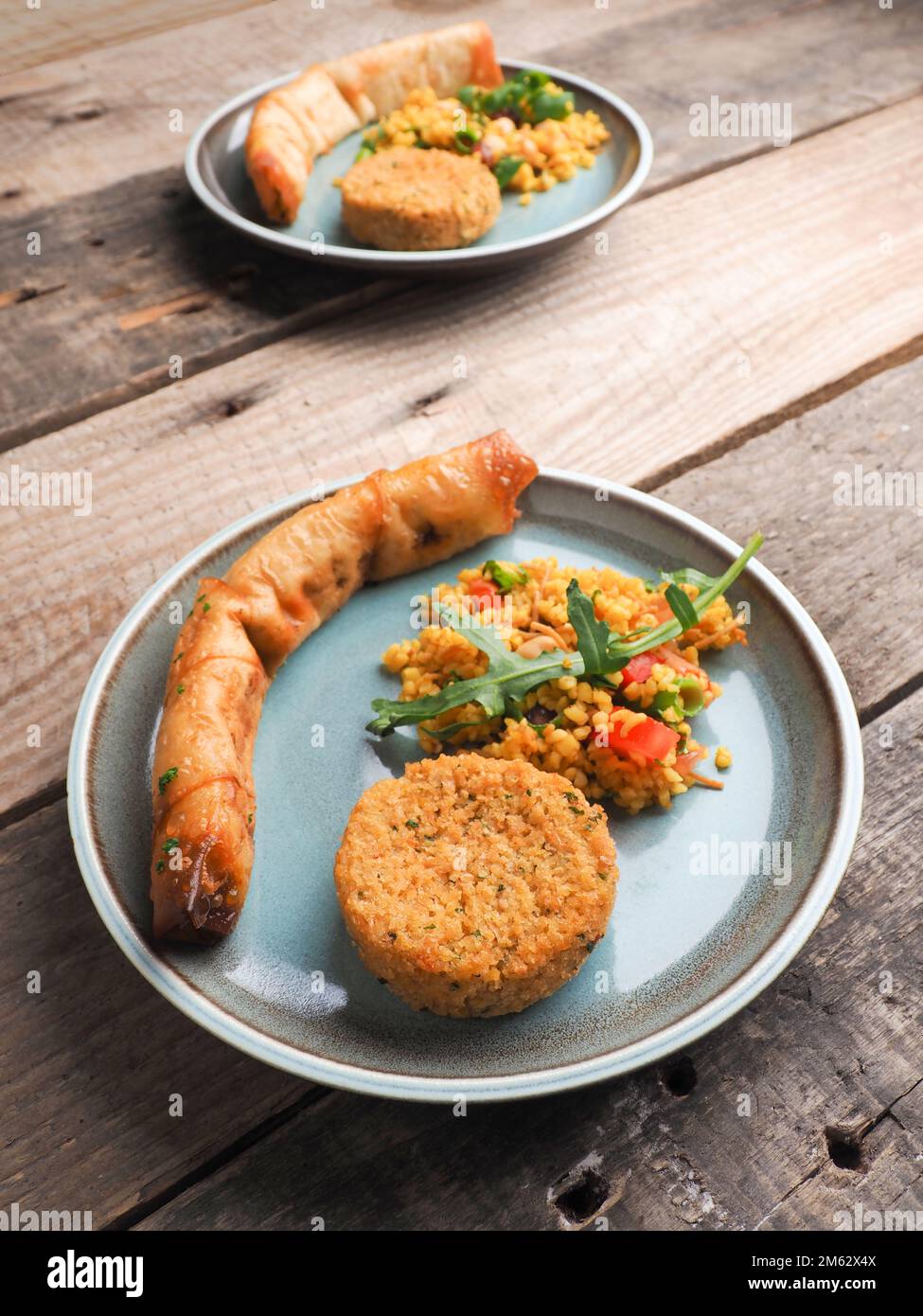 Leckere Falafel mit würzigem Bulgur und einer vegetarischen Teigrolle auf einer Keramikplatte, traditionelle hitzebehandelte Speisen Stockfoto