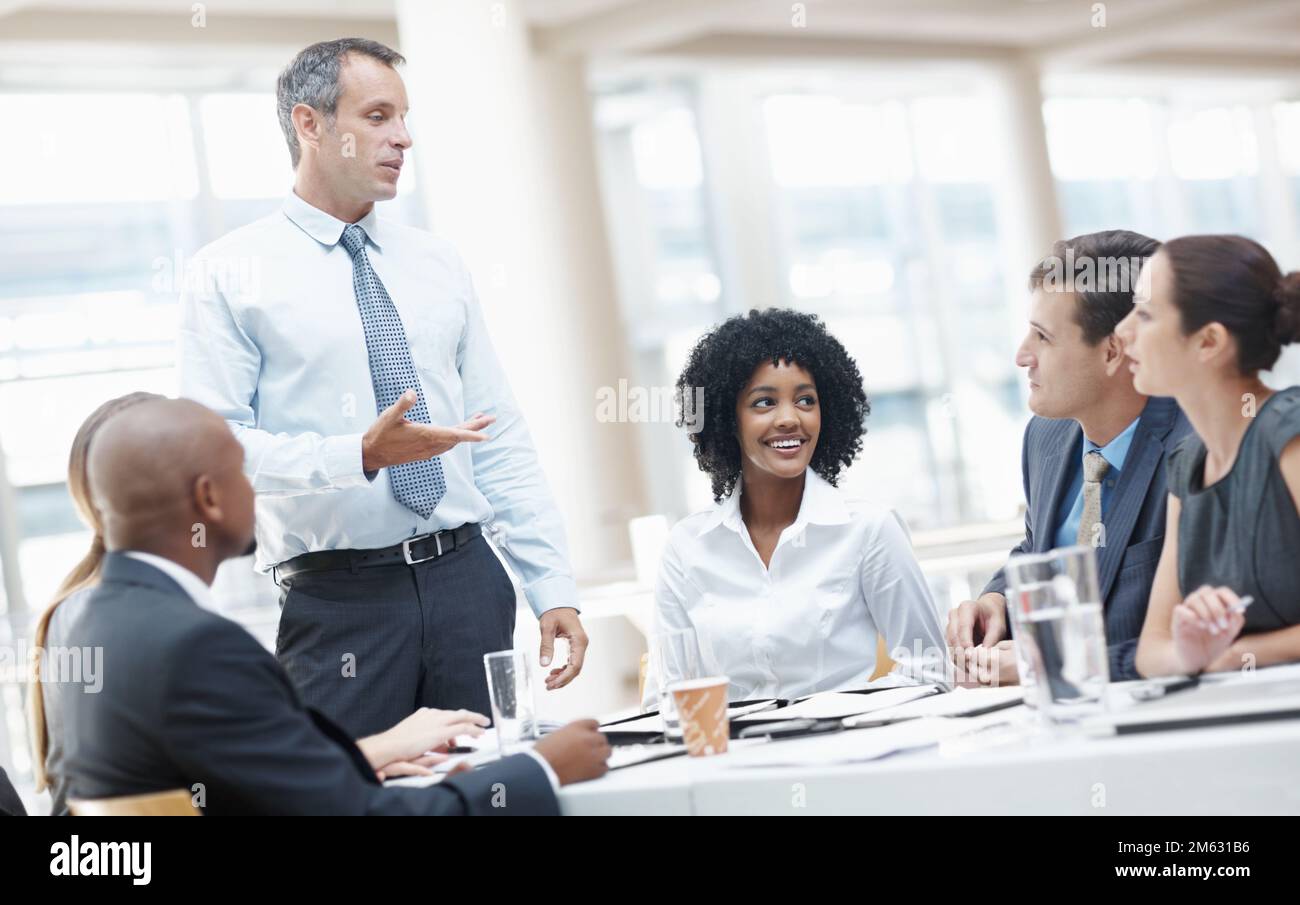 Ich denke, wir hatten ein wunderbares Jahr finanziell. Eine vielfältige Gruppe von Geschäftsleuten, die während eines Meetings von ihrem Vorgesetzten angesprochen werden. Stockfoto