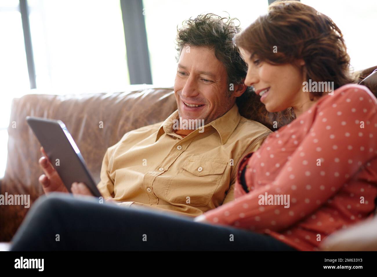 Ihr Wochenende ohne Kabel beginnen. Ein Ehemann und eine Ehefrau, die zu Hause ein digitales Tablet zusammen verwenden. Stockfoto