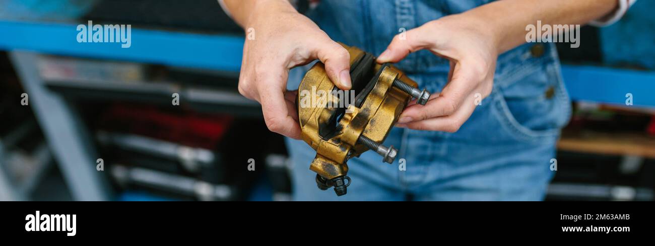 Eine Mechanikerin prüft das Bremssattelsystem in der Garage Stockfoto