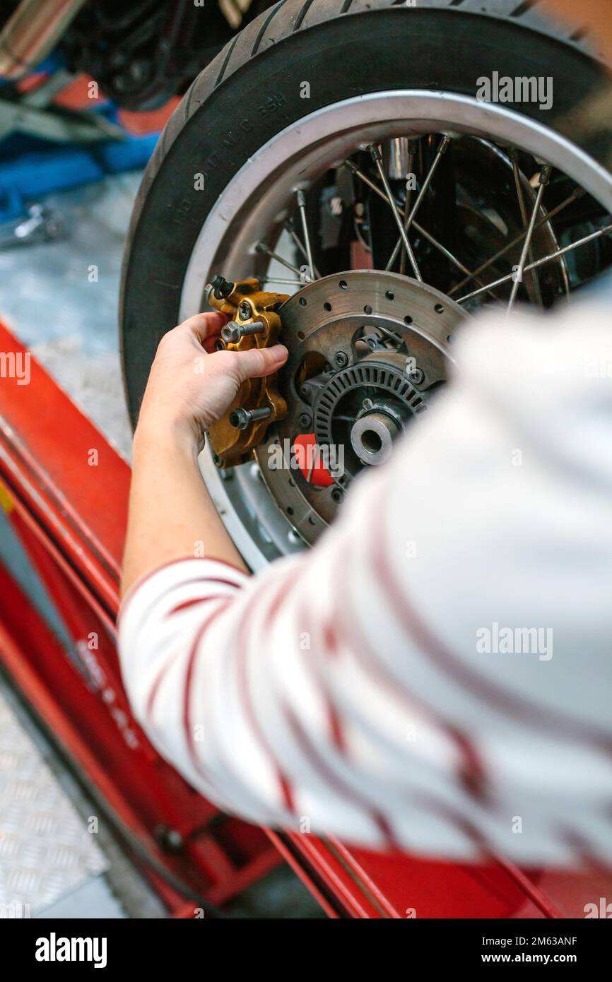 Mechanikerin wechselt Bremssattel im Motorrad Stockfoto