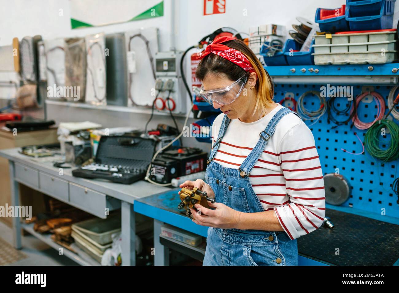 Eine Mechanikerin, die das Bremssattelsystem vor der Werkbank überprüft Stockfoto