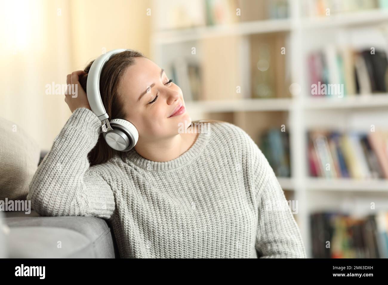 Glücklicher Teenager mit Kopfhörern, der zu Hause Musik hört Stockfoto