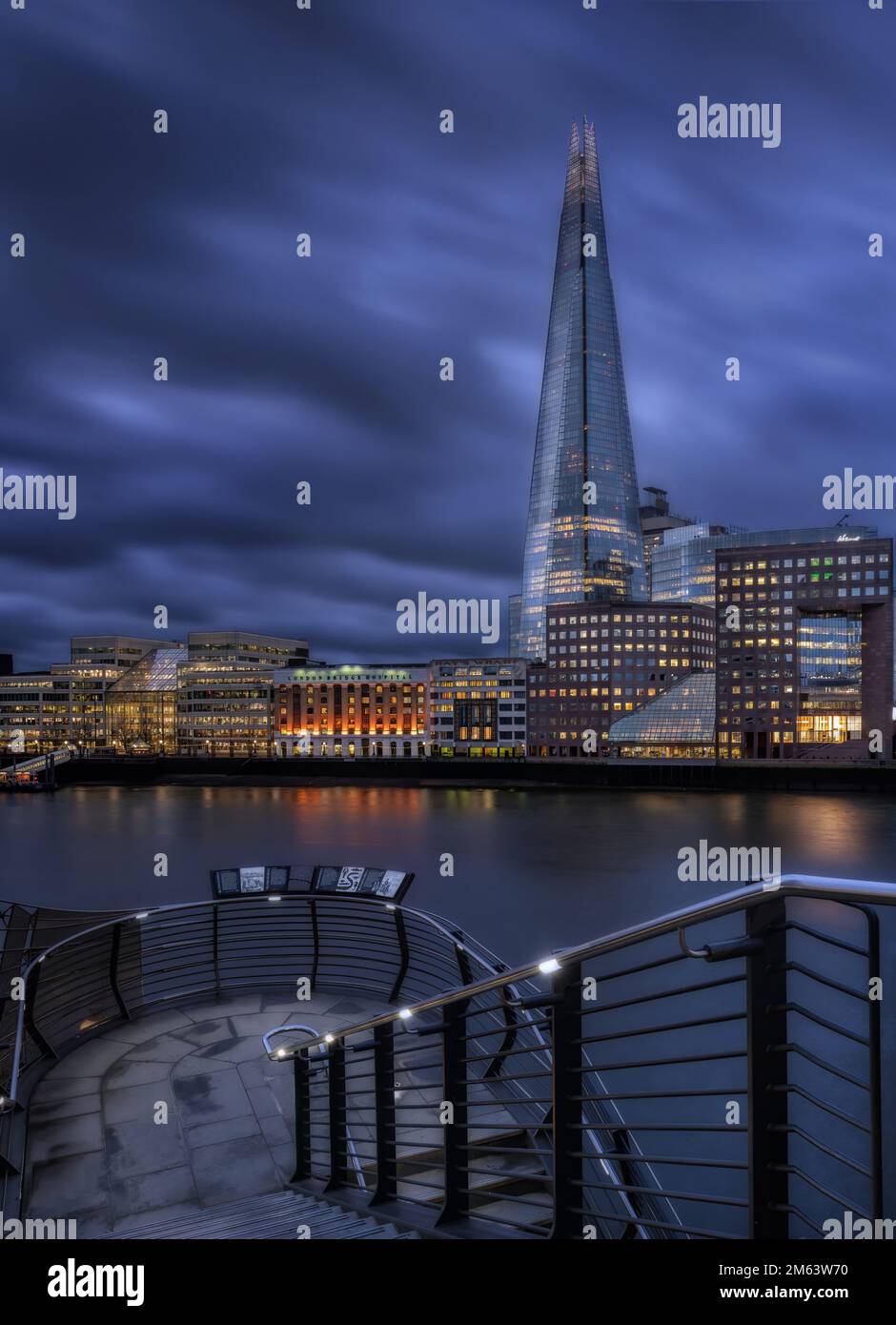 Das Shard erhebt sich über der Themse und der Londoner Skyline während der Blauen Stunde, während die Stadtlichter das Ufer beleuchten. Foto im Porträtformat Stockfoto