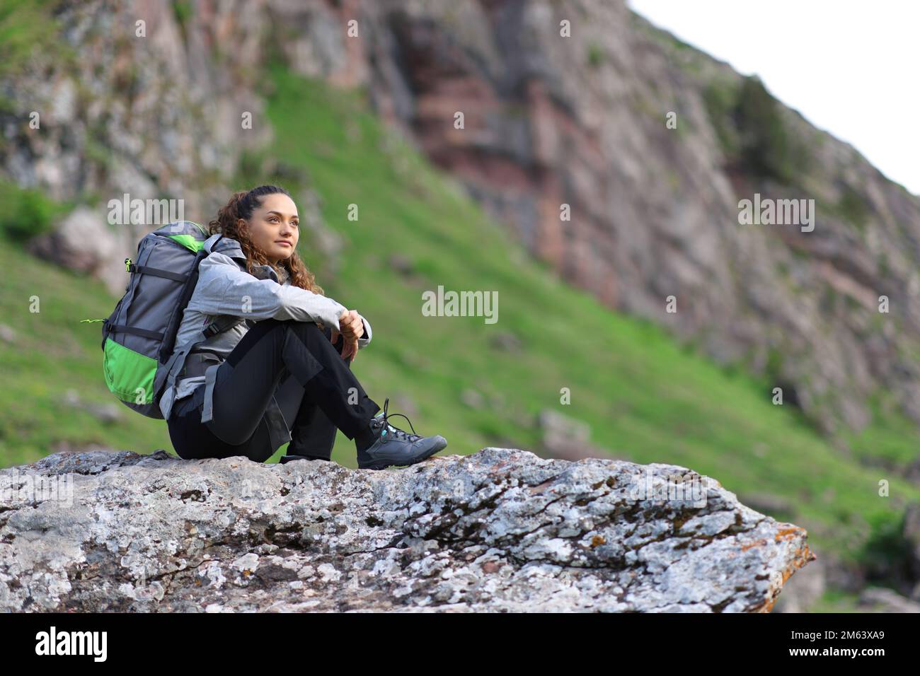 Hikker sitzt auf einem Felsen und denkt über die Aussicht auf den Berg nach Stockfoto