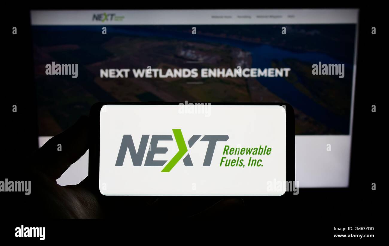 Person, die ein Smartphone mit dem Logo des US-Unternehmens NEXT Renewable Fuels Inc. Auf dem Bildschirm vor der Website hält. Konzentrieren Sie sich auf das Display des Telefons. Stockfoto