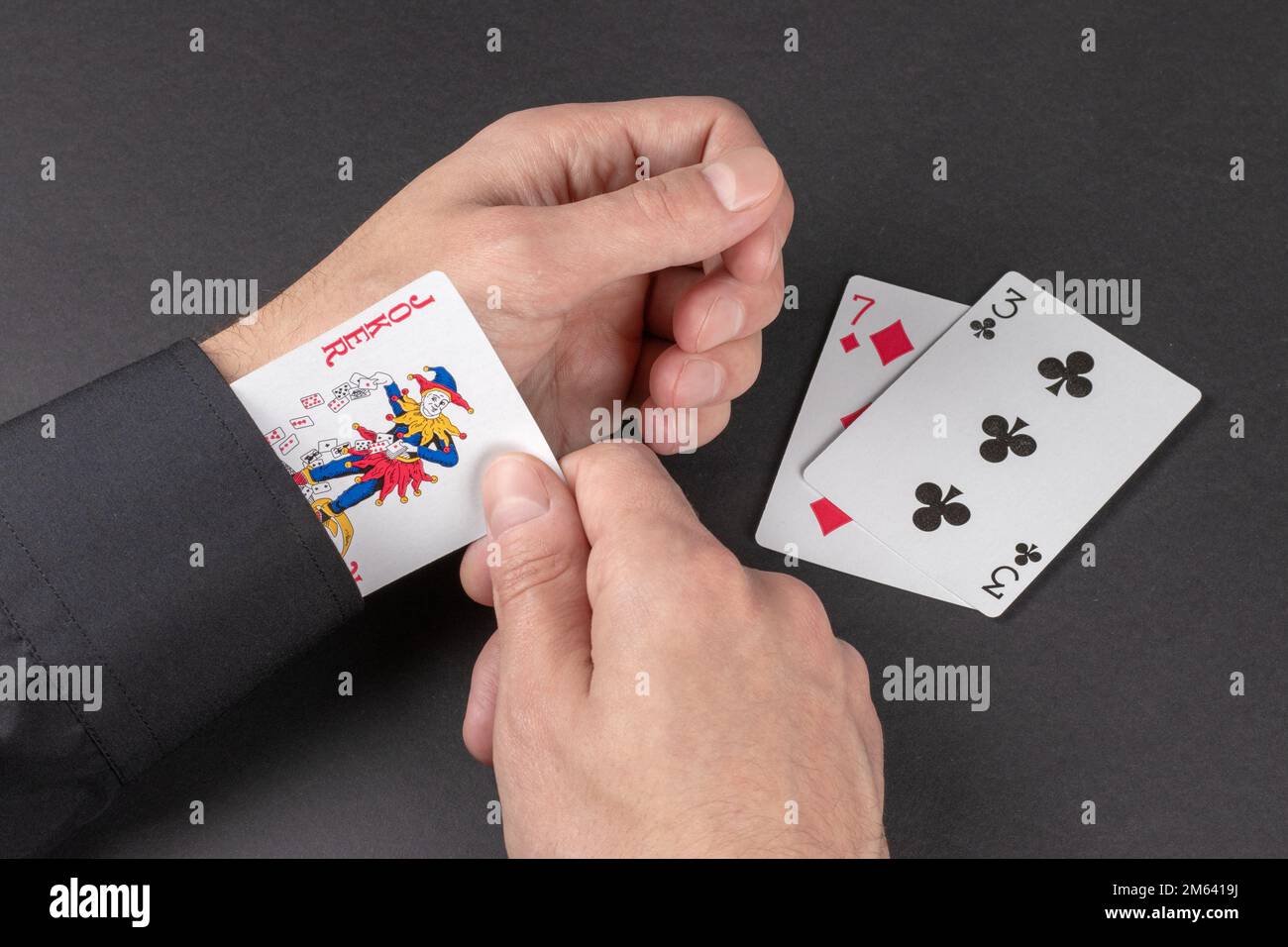 Konzept - Joker-Karte im Ärmel auf dunklem Hintergrund. Stockfoto