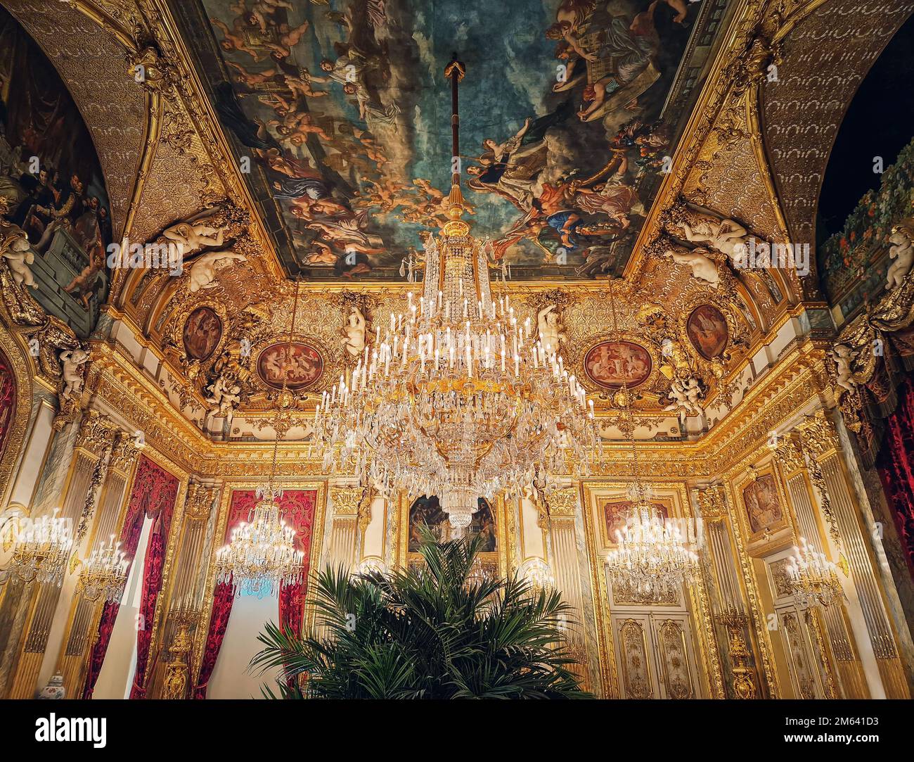 Wunderschön eingerichtete Napoleon Apartments im Louvre Palace. Königliche Familienzimmer mit kardinalroten Vorhängen, goldverzierten Wänden, Gemälden und Kristalltafel Stockfoto