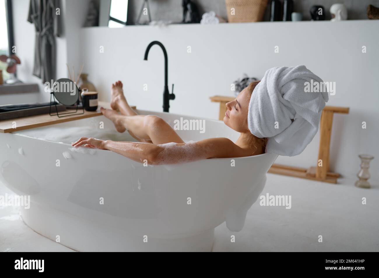 Blick von oben auf eine Frau, die sich im Bad mit Seifenschaum entspannt Stockfoto