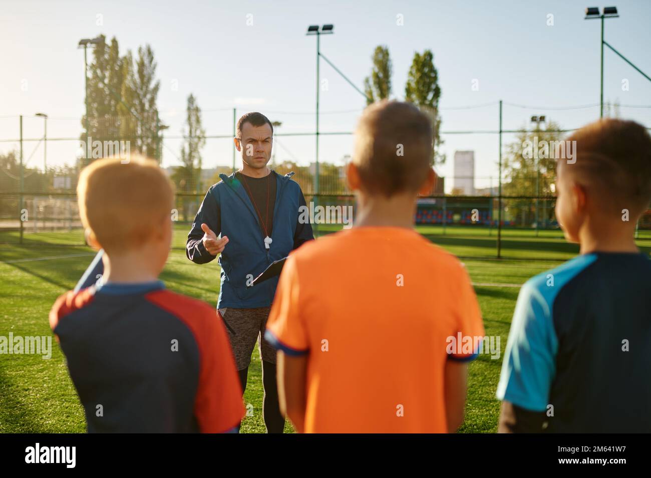 Junger Fußballtrainer, der Kindern auf dem Fußballfeld beibringt Stockfoto