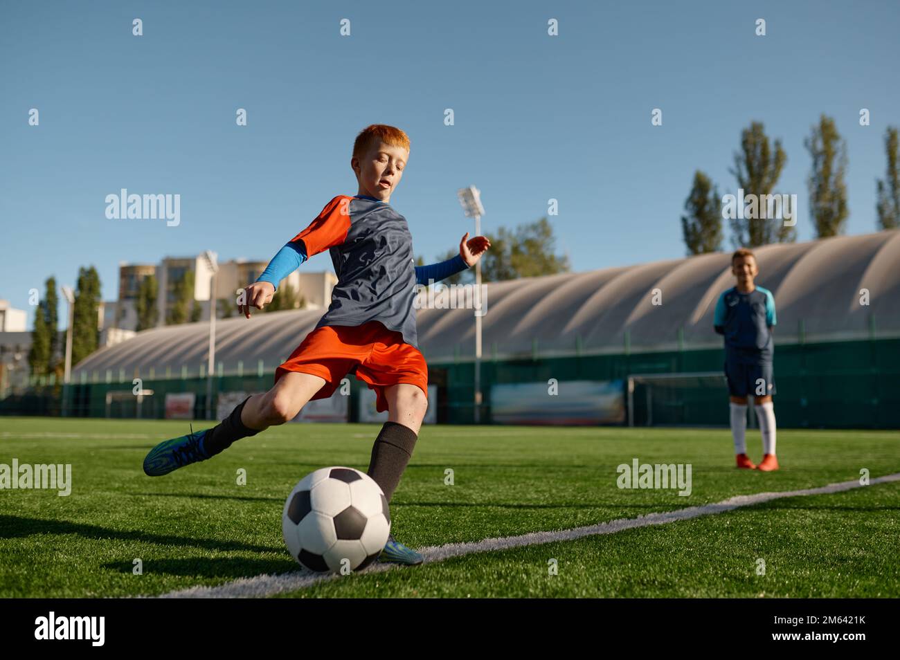 Ein Junge spielt Football auf dem Feld und tritt Fußball Stockfoto