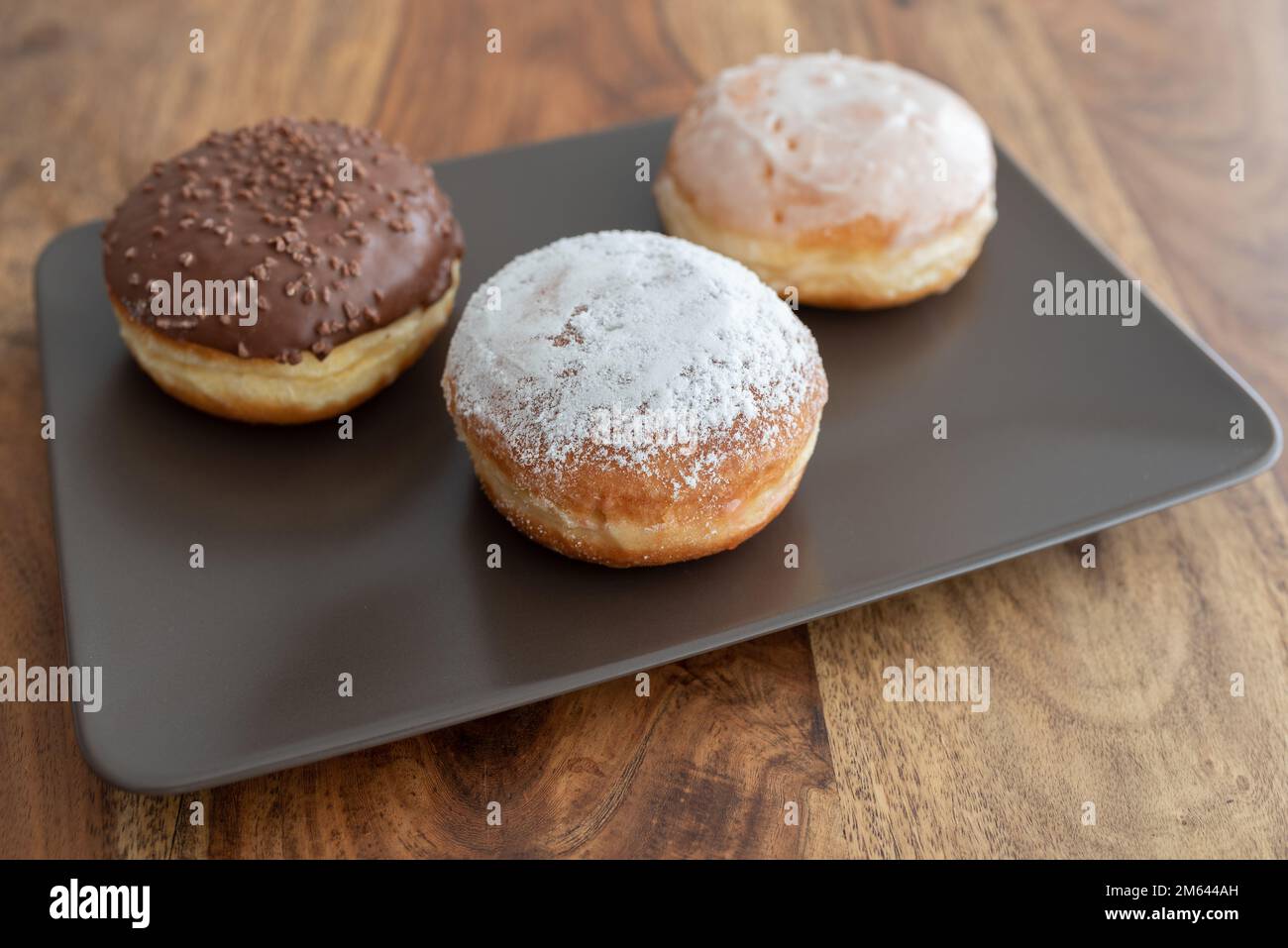 Blick aus dem hohen Winkel auf deutsche Donuts, bekannt als Berliner, mit verschiedenen Füllungen und Vereisungen auf der Platte Stockfoto