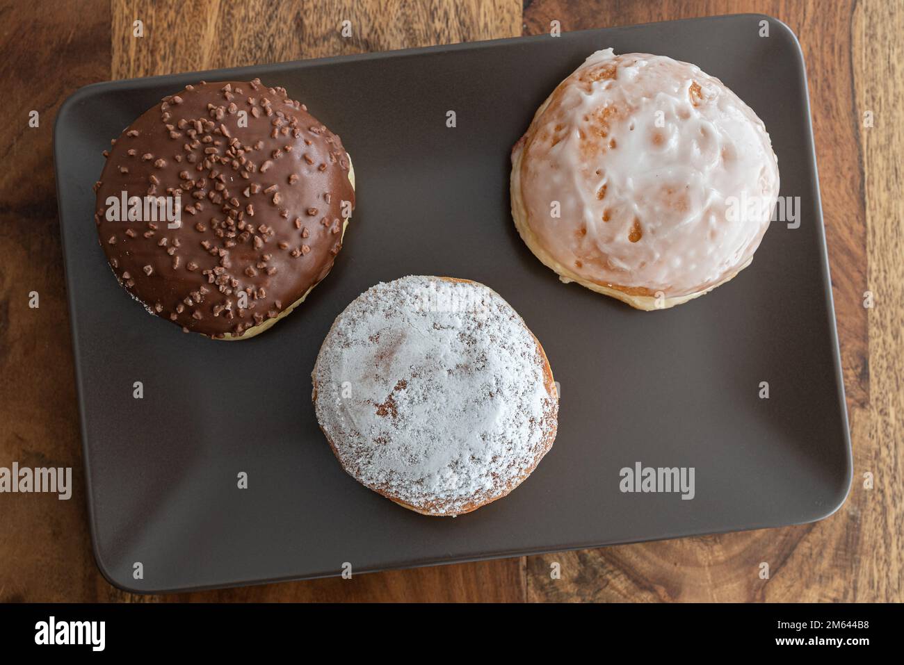 Top-down-Blick auf deutsche Donuts, bekannt als Berliner, mit verschiedenen Füllungen und Eis auf der Platte Stockfoto