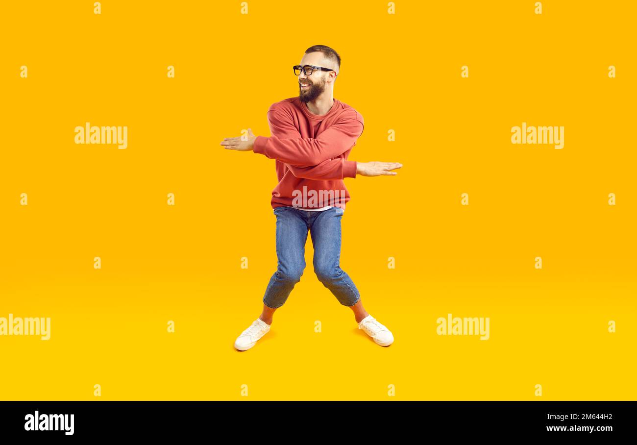 Fröhlicher, lustiger und energiegeladener Mann, der humorvolle Witzfiguren auf orangefarbenem Hintergrund zeigt. Stockfoto