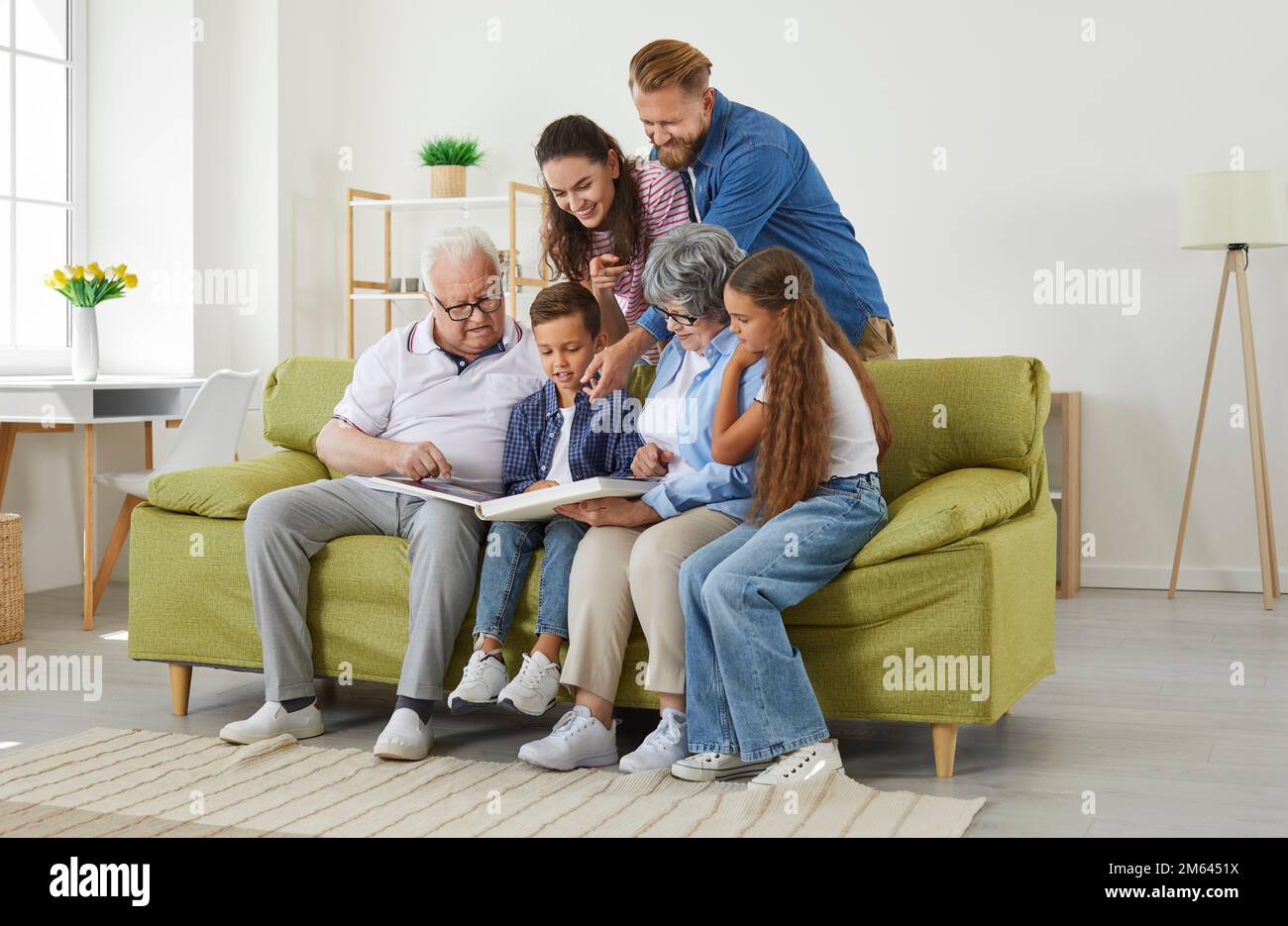 Große Familieneltern, Kinder, Großeltern, die ein Familienfoto suchen, sitzen zusammen im Wohnzimmer. Stockfoto