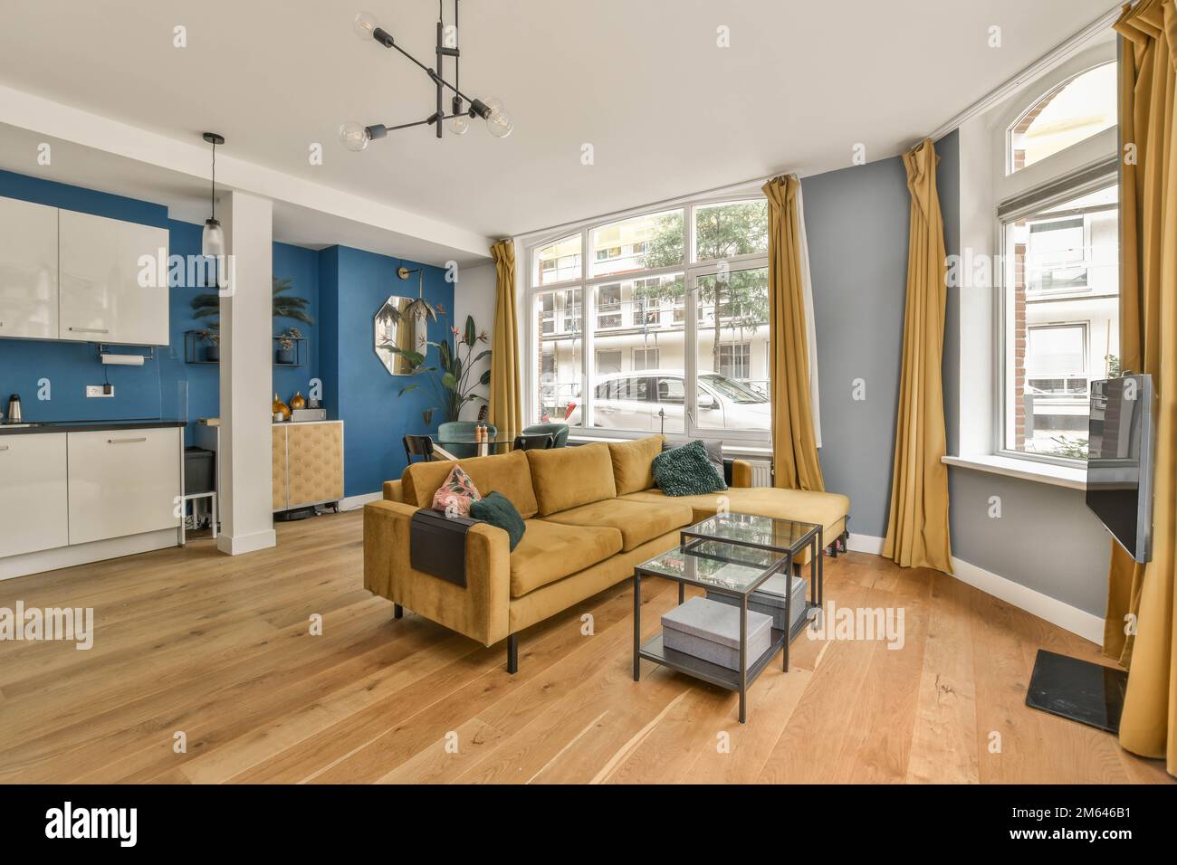 Ein Wohnzimmer mit blauen Wänden und Holzfußboden. Das Zimmer verfügt über eine gelbe Couch, einen Couchtisch, zwei Stühle und eine Stockfoto