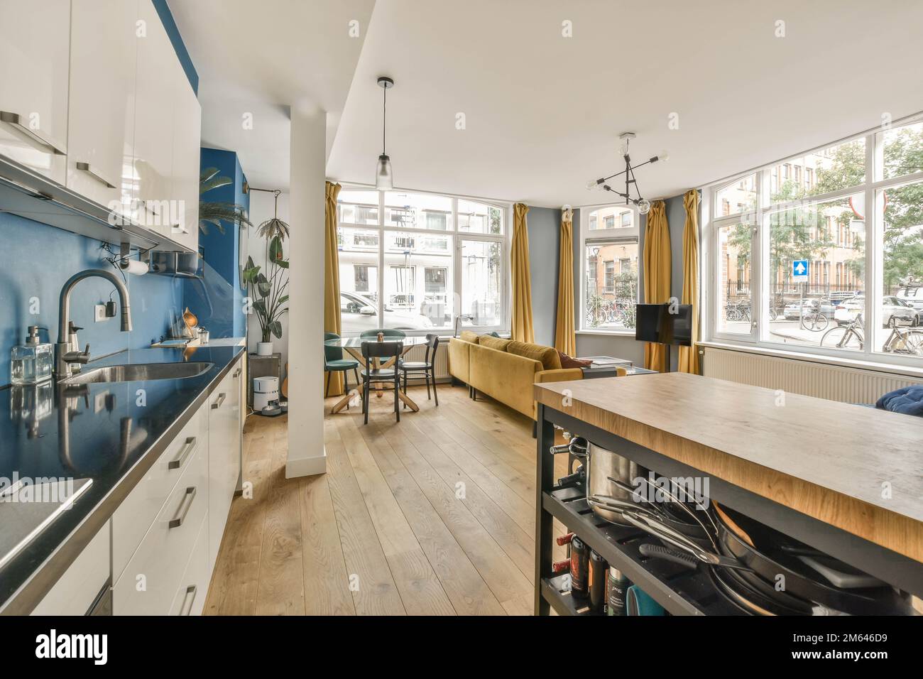 Küche und Essbereich in einem Haus mit blauen Wänden, Holzfußboden und weißen Schränken an der Wand Stockfoto
