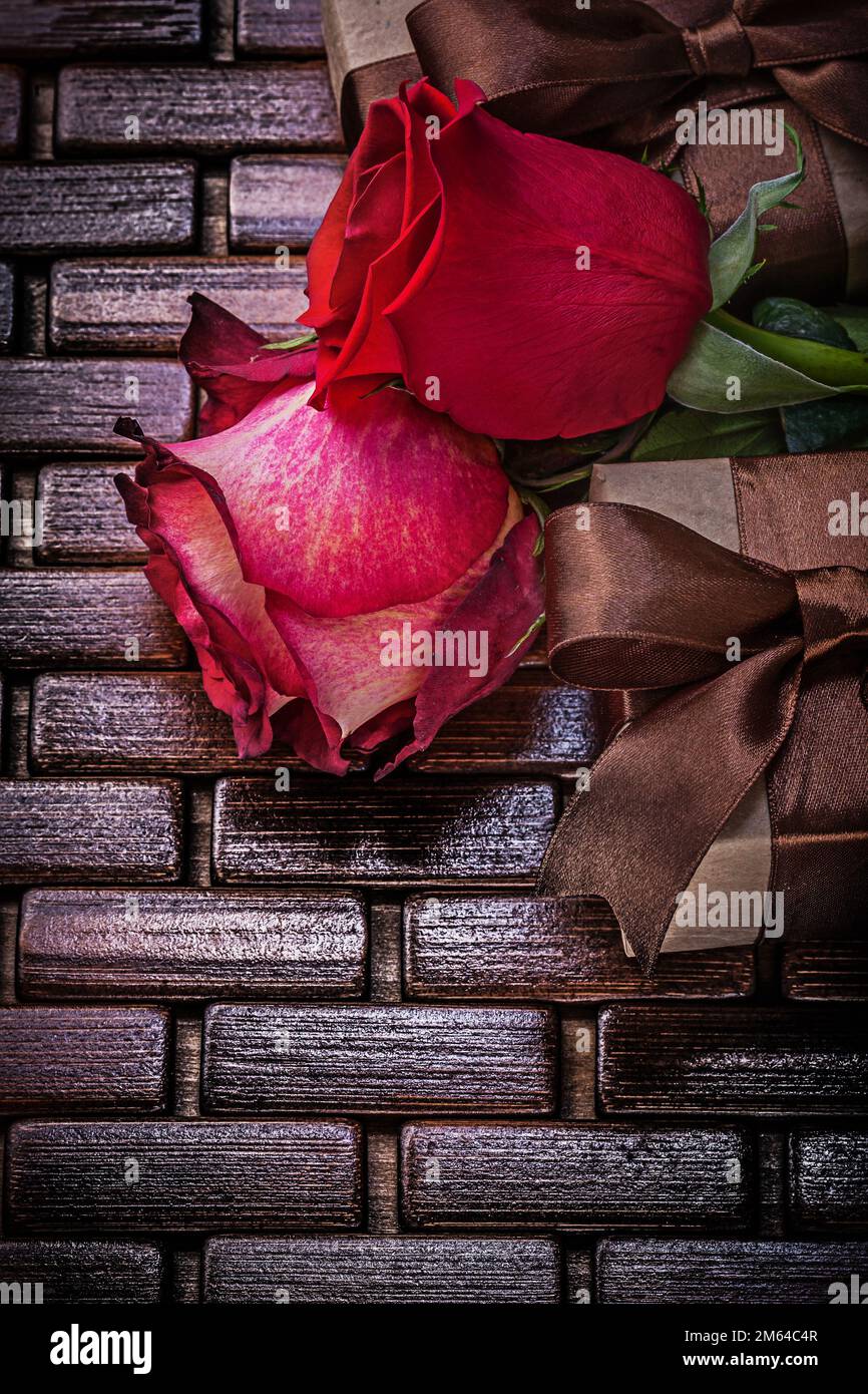 Natürlich duftende Rosen verpackte Geschenkboxen auf einer Holzmatte aus Korbweide. Stockfoto