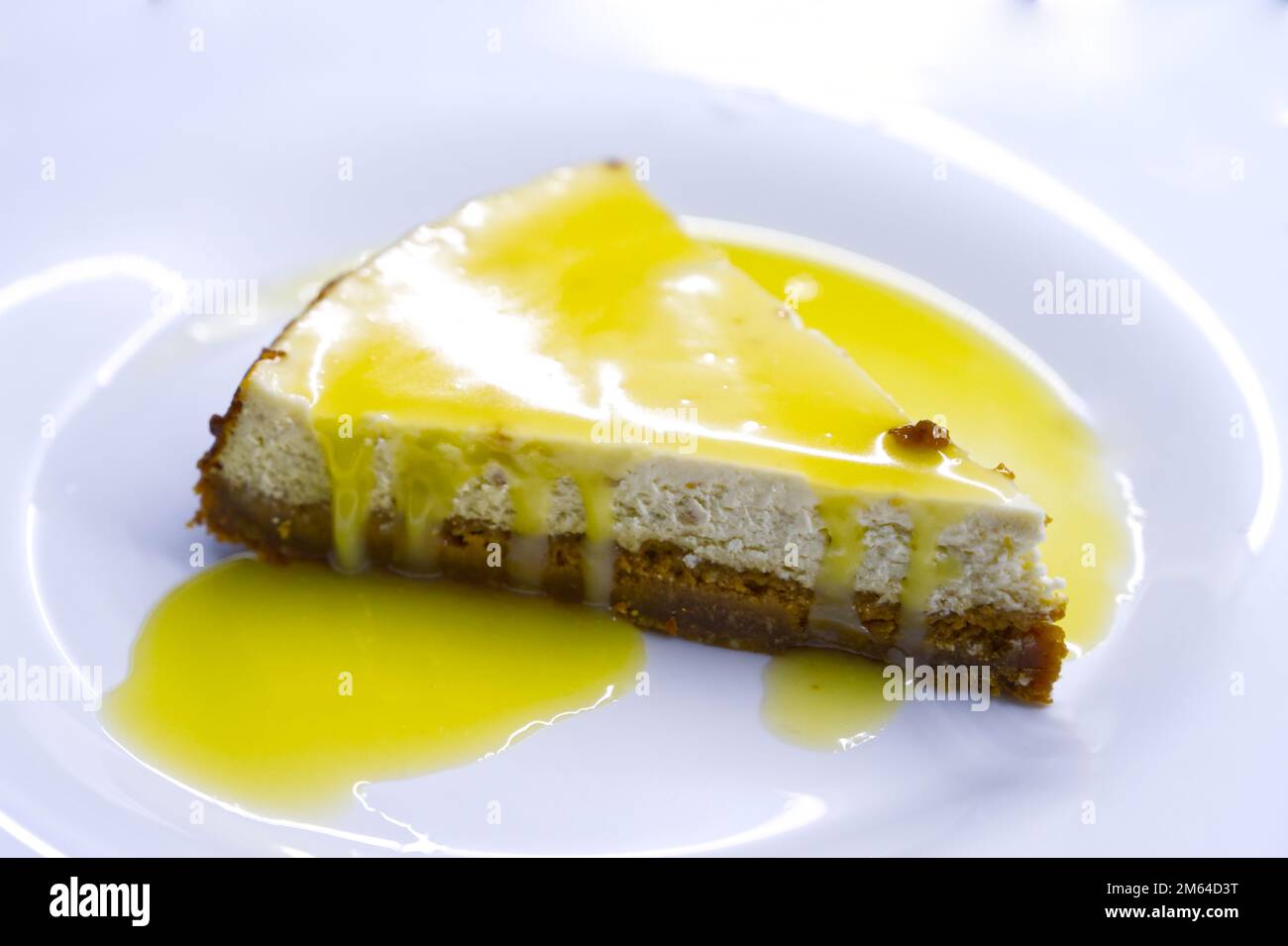 Käsekuchen, ein klassischer New Yorker Käsekuchen auf weißem Hintergrund. Ein Stück leckeren Kuchen auf einem weißen Teller, serviert mit Vanille-Zuckerguss Stockfoto