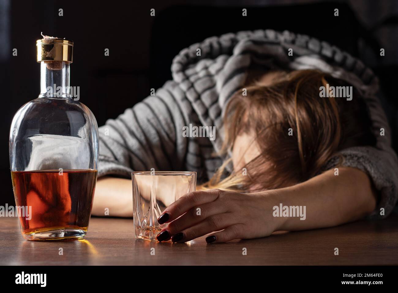 Betrunkene betrunkene Frau, die in der Nähe von WhiskeyGlas schläft, weibliche starke Trinkerin