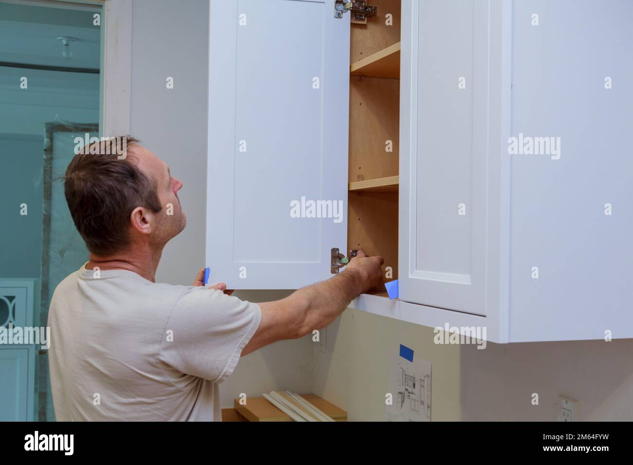 Zimmermannsarbeiter, der die Tür zum Küchenschrank im neuen Heim repariert Stockfoto