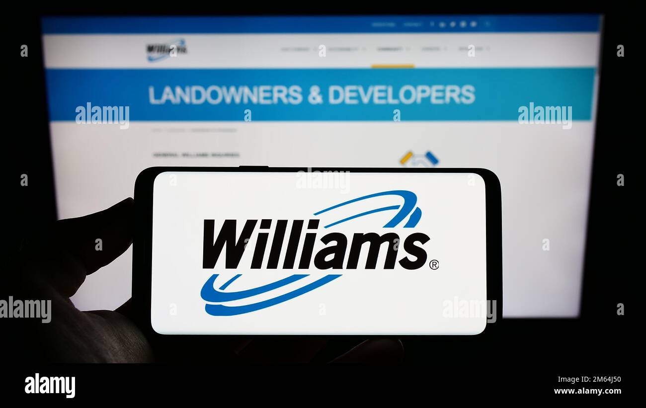 Person, die ein Mobiltelefon mit dem Logo des US-amerikanischen Energieunternehmens Williams Companies Inc. Auf dem Bildschirm vor der Unternehmenswebseite hält. Konzentrieren Sie sich auf das Display des Telefons. Stockfoto