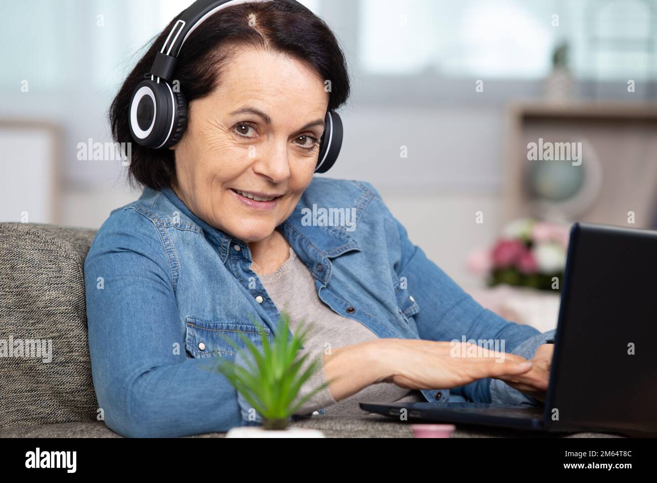 Seniorin mit Laptop und Kopfhörern Stockfoto