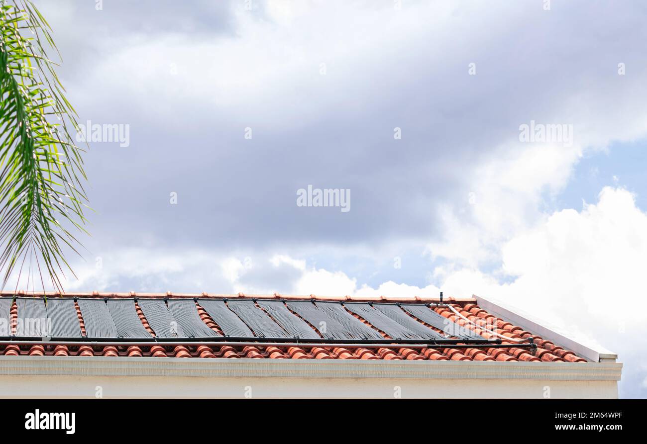 Wasserheizung auf dem Dach des Hauses an einem sonnigen und bewölkten Tag. Bild: Erneuerbares Konzept. Stockfoto